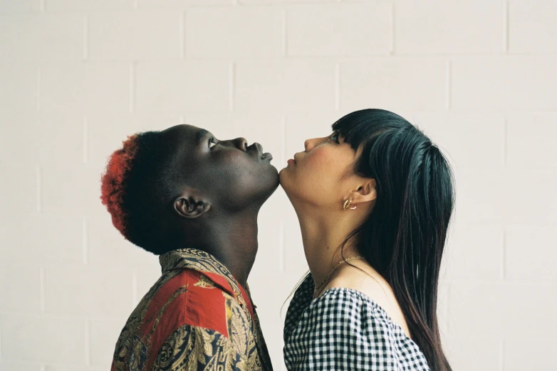 two woman facing each other on a white brick wall