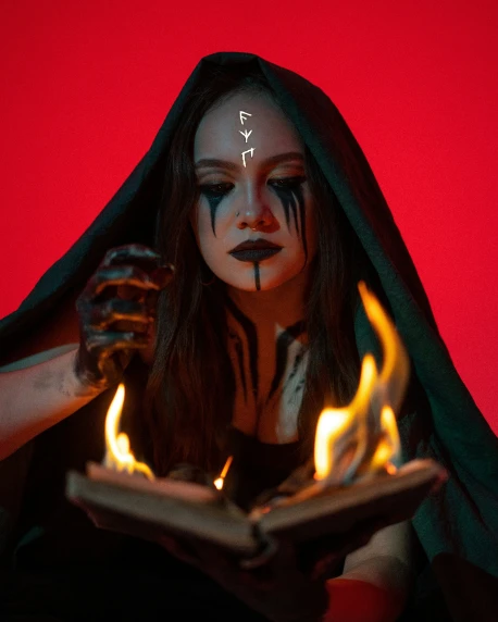 a young woman with face paint on holding a tray full of flames