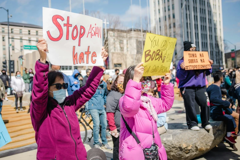 people holding signs in a protest outside in front of large buildings