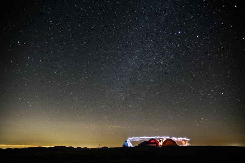 a field with two tents under the stars