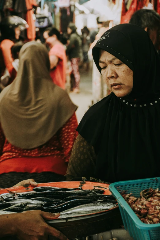 a lady wearing a hijab is at an outdoor market