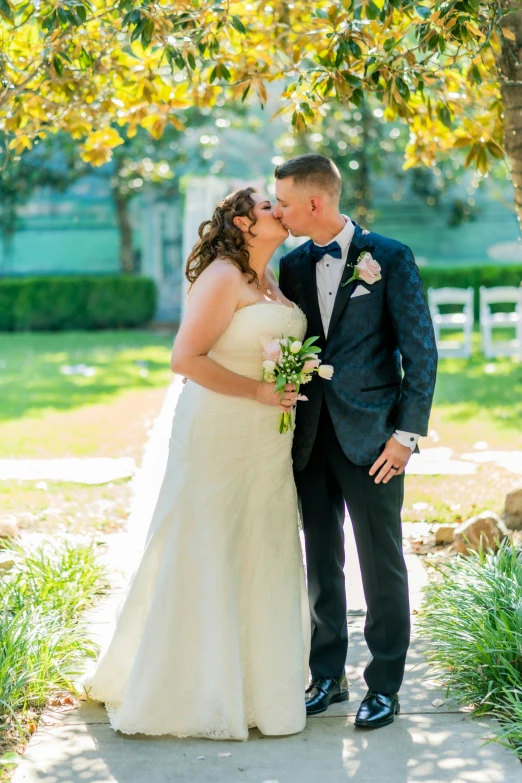 a bride and groom posing under a tree at their wedding