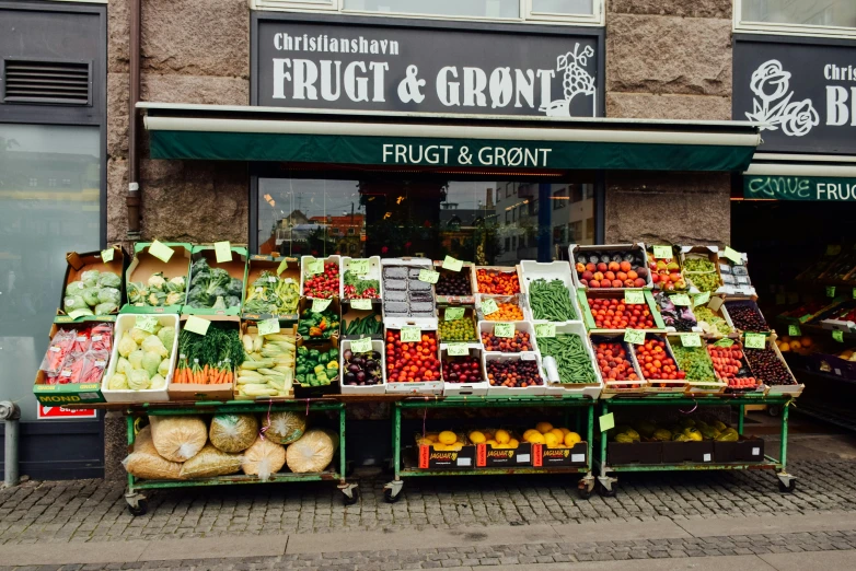 the fruits and vegetables stand is outside on the sidewalk