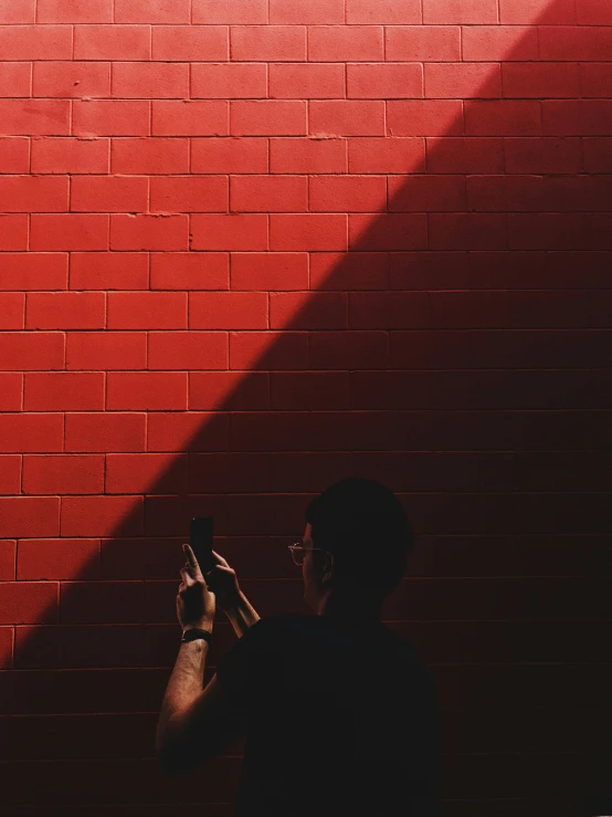 a man taking a selfie against a red brick wall