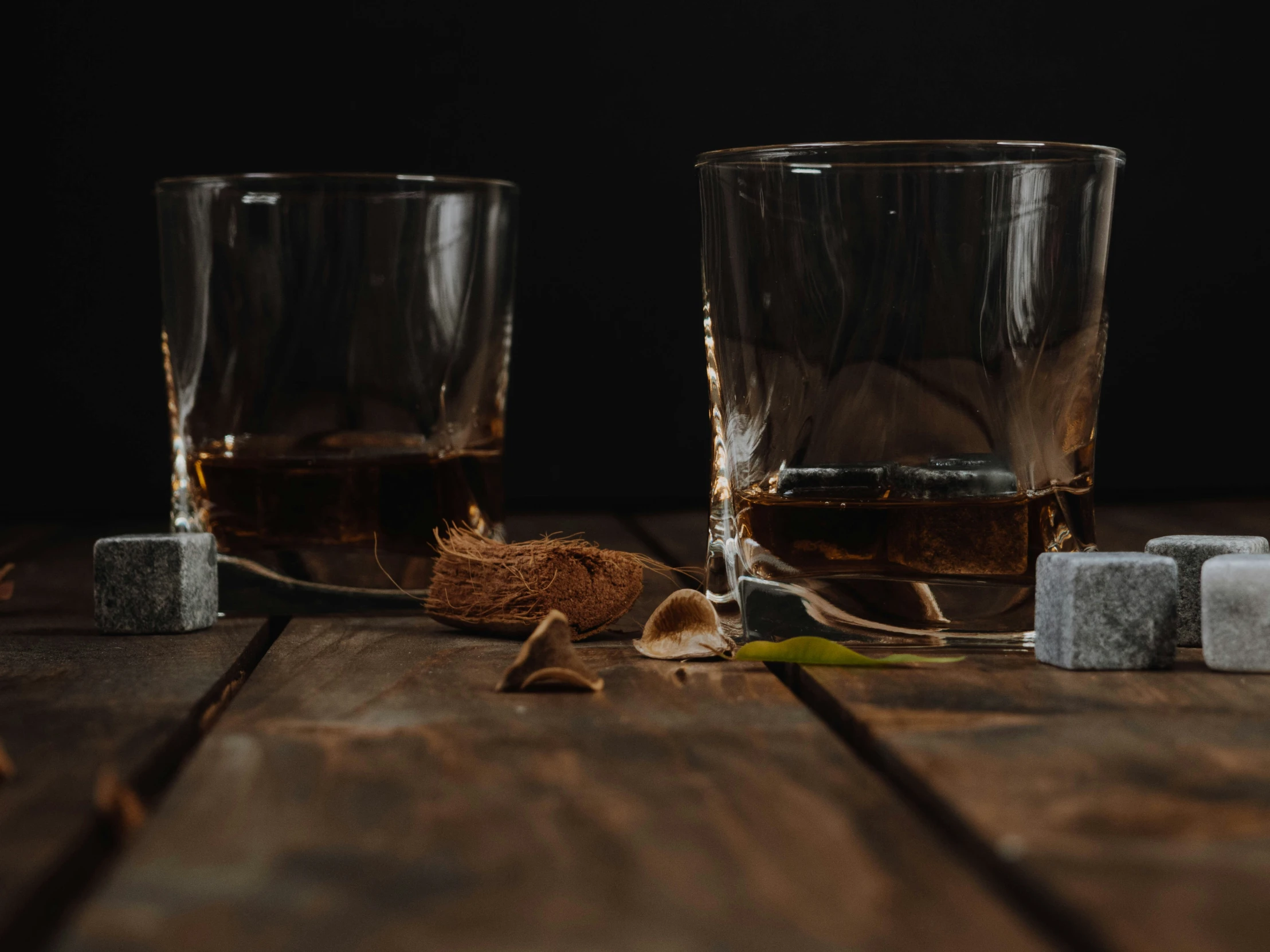 two glass cups and blocks of ice on a wooden table