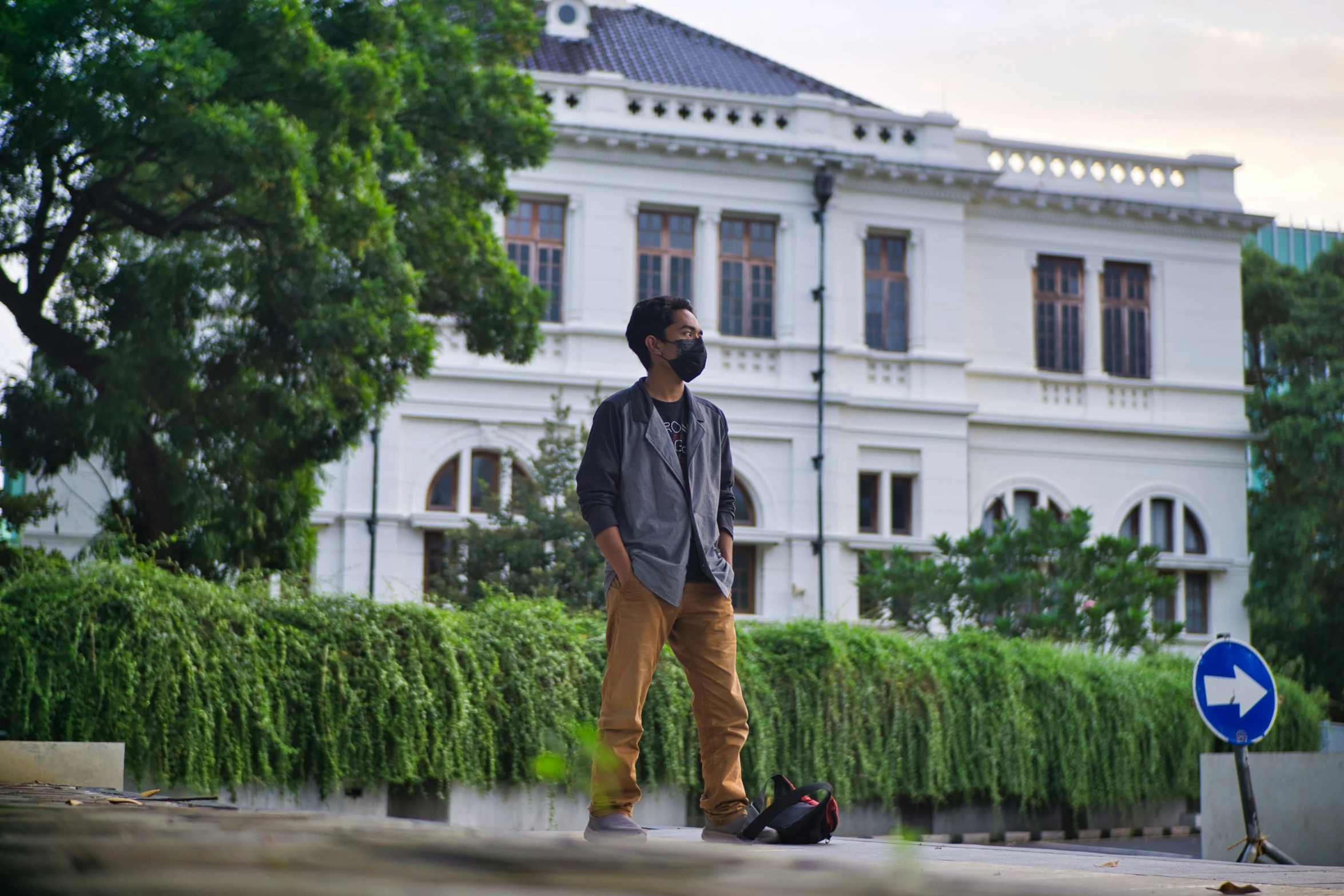 man in grey jacket with luggage standing next to a large building