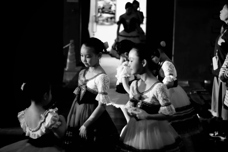 three little girls dressed up in dresses are talking