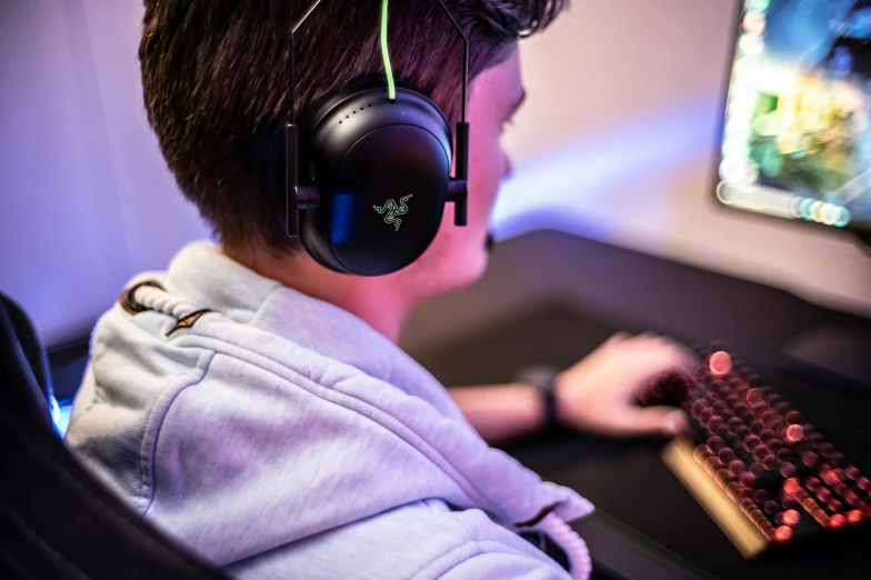 young man sitting in front of computer with headphones and looking at computer screen