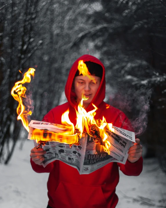 a man in a red jacket holding a newspaper while wearing fire