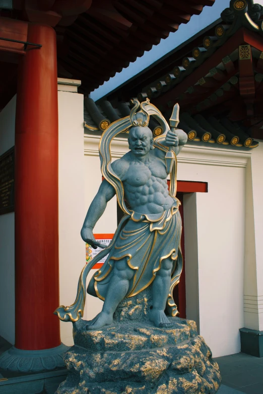 an asian statue with a sword in the foreground