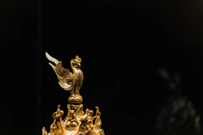 gold bird on top of a golden tower with other figurines