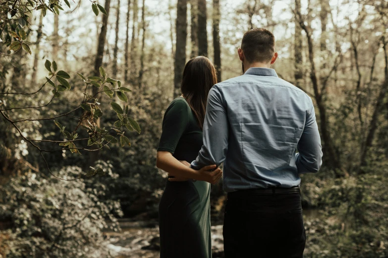 a man and woman standing in a forest together