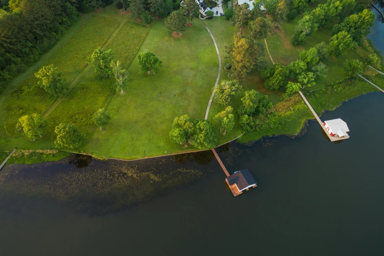 an aerial po of a boat dock and a green lawn area next to the water