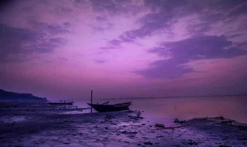 purple sky above some empty beached boats