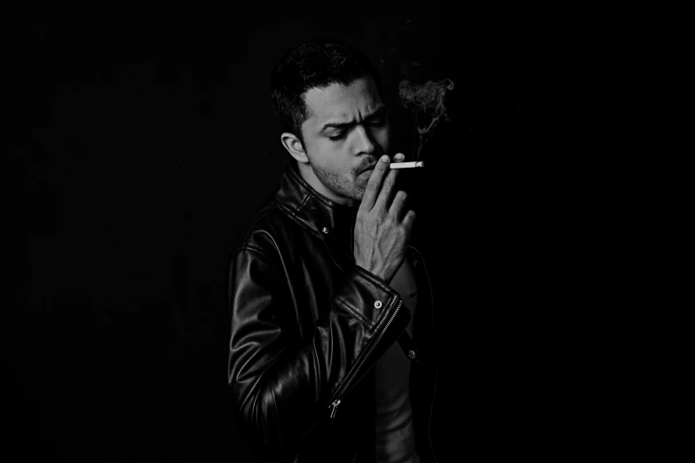 a man holding a cigarette and smoking on a cell phone