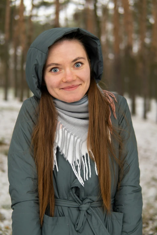 young woman standing in snow with trees in the background