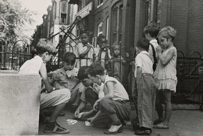 group of people standing and sitting next to each other on the sidewalk