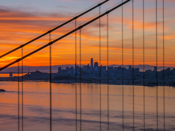 a city with a bridge next to a river at sunset