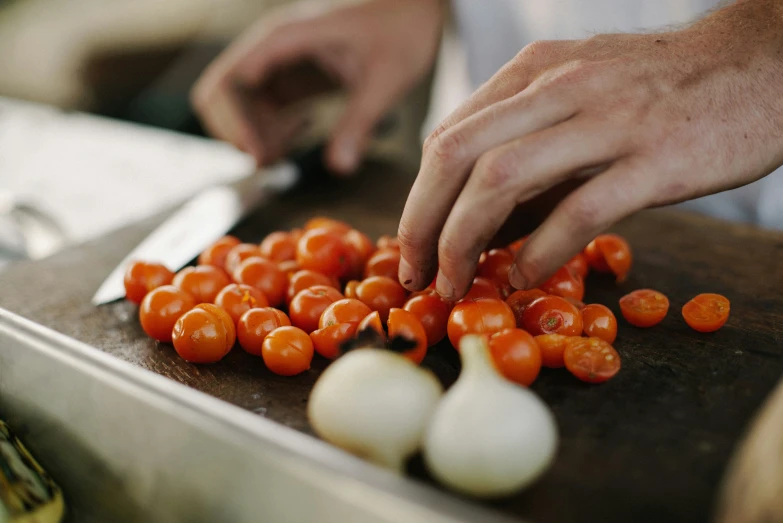 a person reaching for soing on a  board with vegetables on top