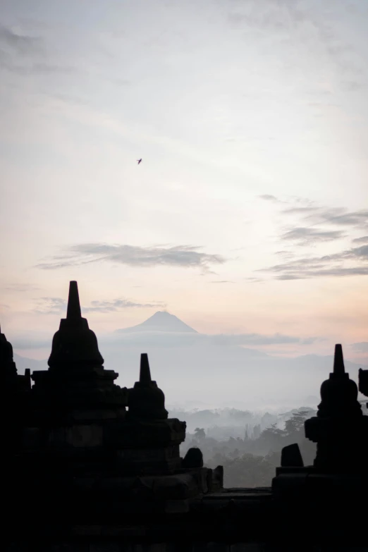 a lone bird flying in the distance between many stone structures