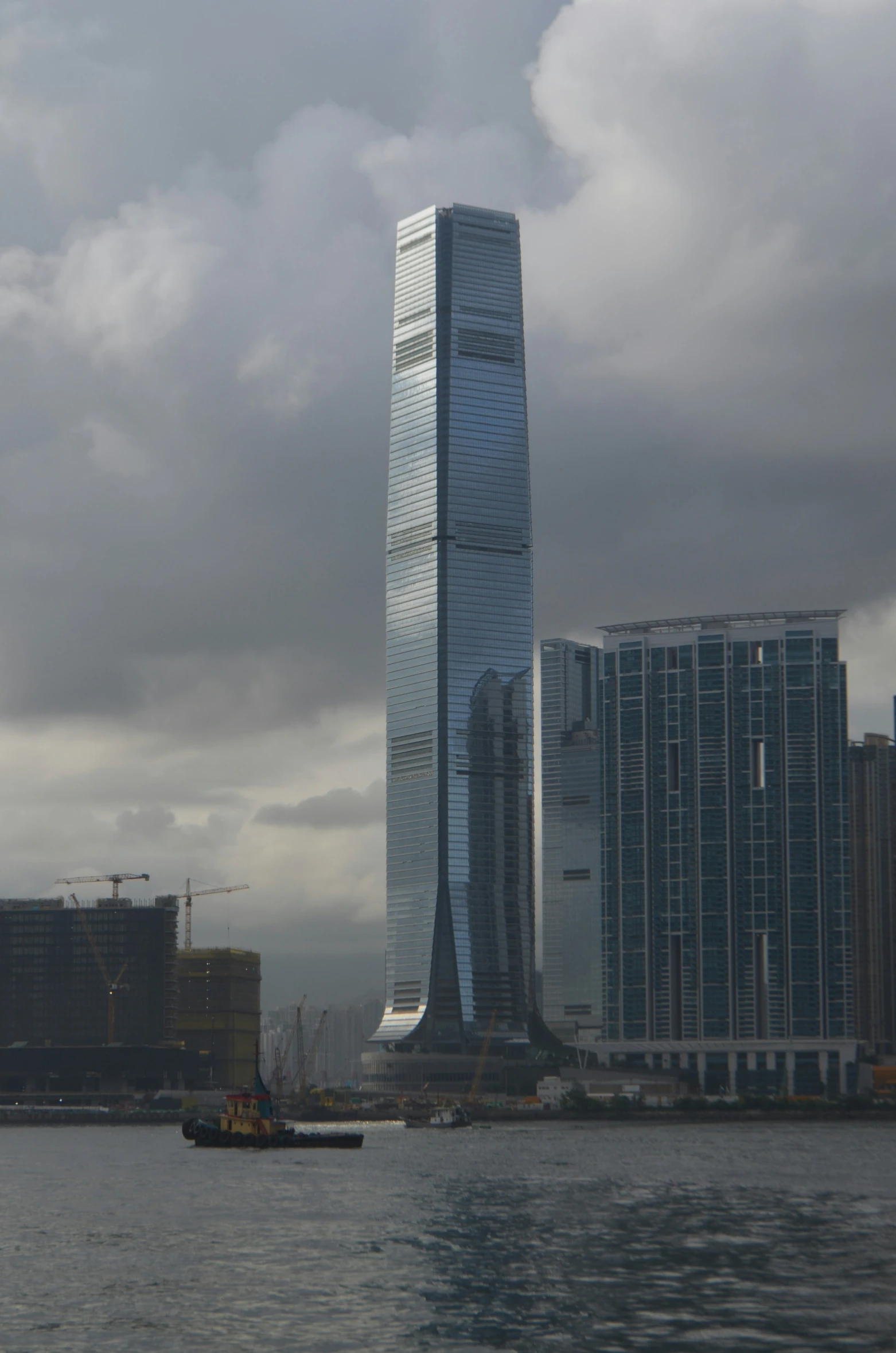 boat sailing past large high - rise buildings on a cloudy day