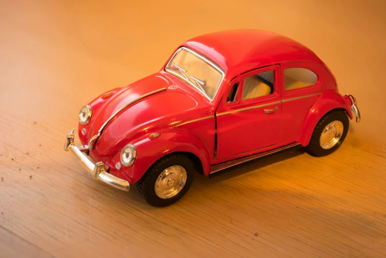 small red toy car is on top of wood table