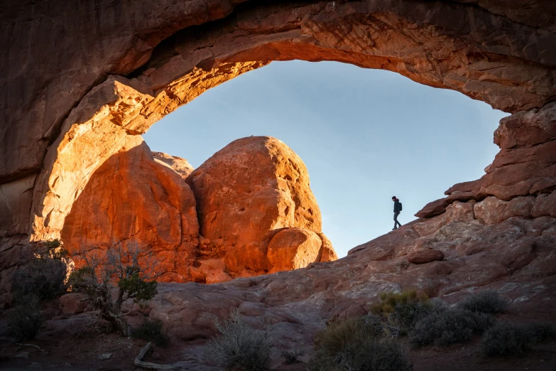 the silhouette of a man standing in an arch in a mountain