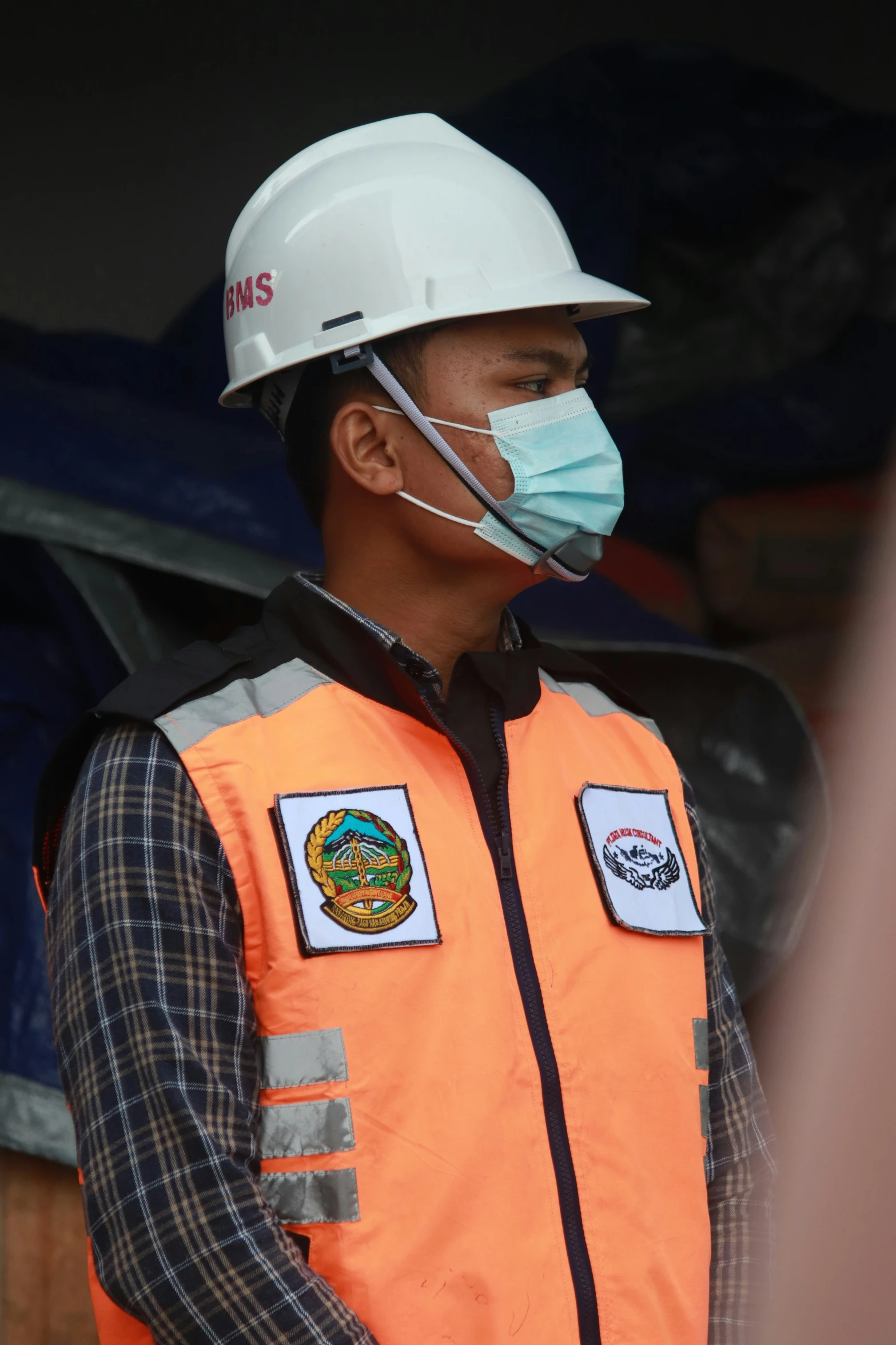 a construction worker wearing a protective mask, vest and orange jacket