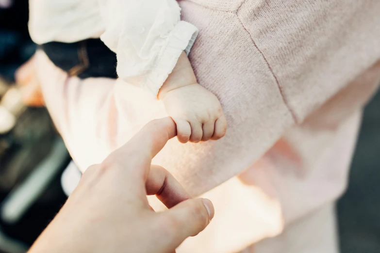 a mother holding her infant holding their hand