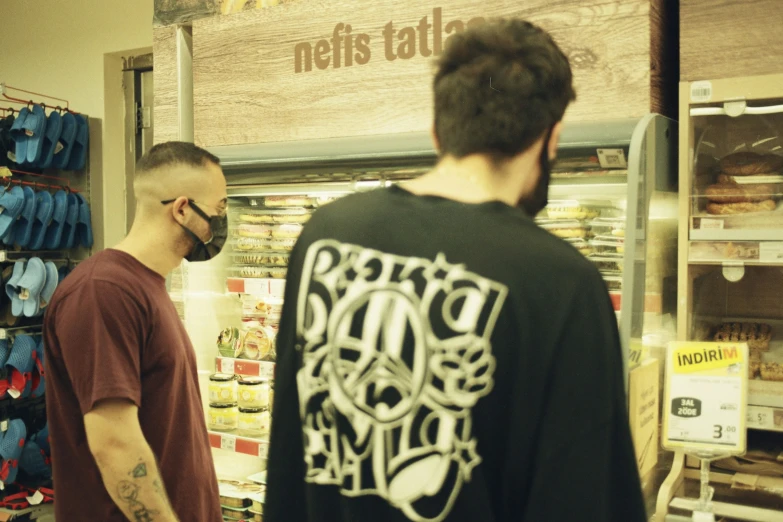 a man with a beard stands in front of a shop filled with items