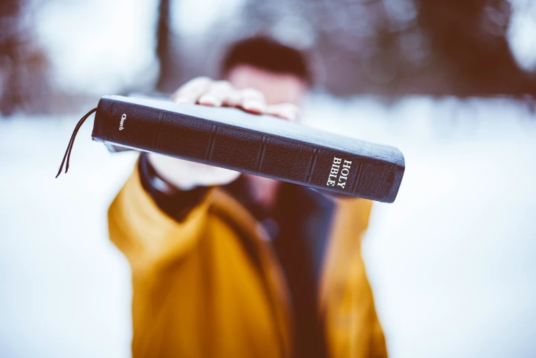 man holding up an open bible with a hand