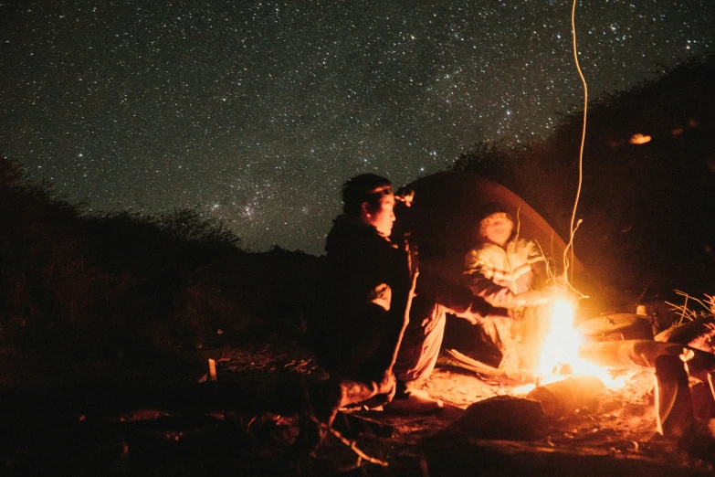 a group of people gathered around a campfire in the wilderness