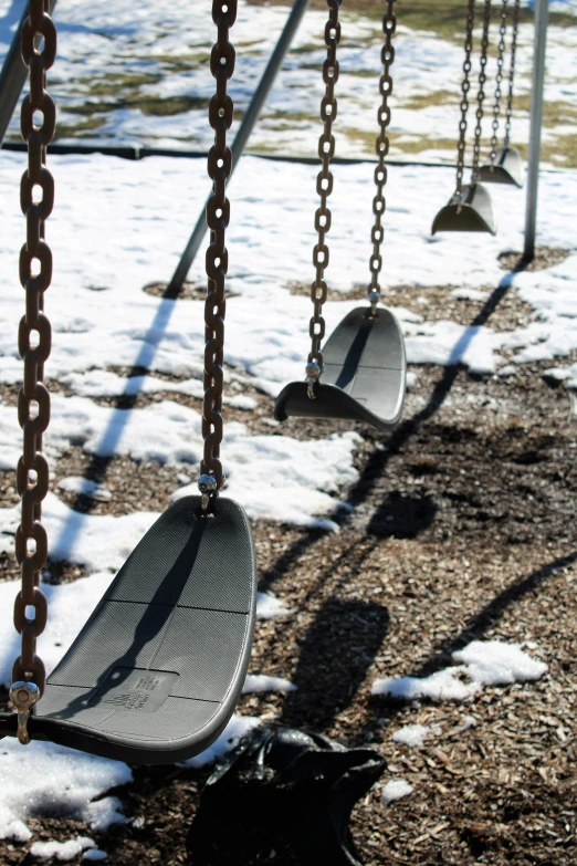 some swings hanging from chain in the snow