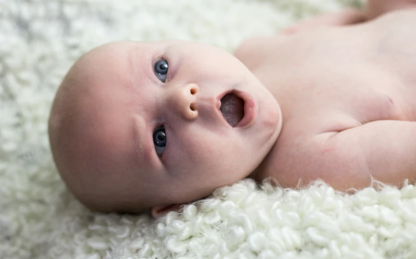 a baby is laying on a white blanket