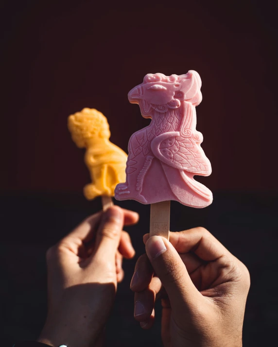 two hands holding some ice cream on sticks