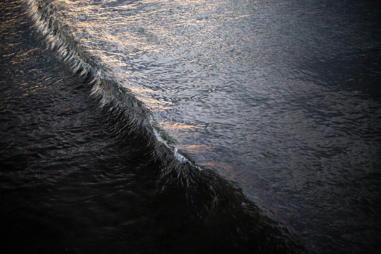 close up of the waves on the water with a lighthouse in the background