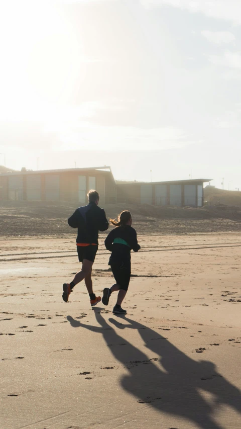 two people running in the sand near an airplane