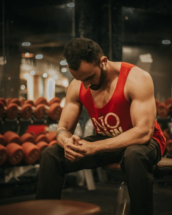 a man in red vest and black pants sitting on bench