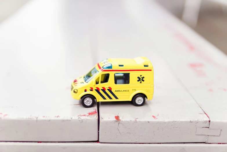 a small toy yellow ambulance on a table