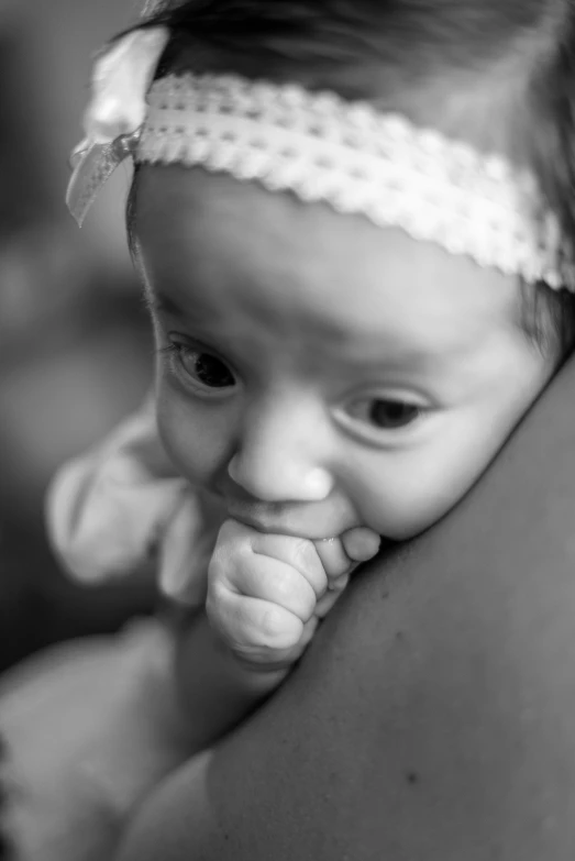 a baby is looking at the camera while covering her mouth