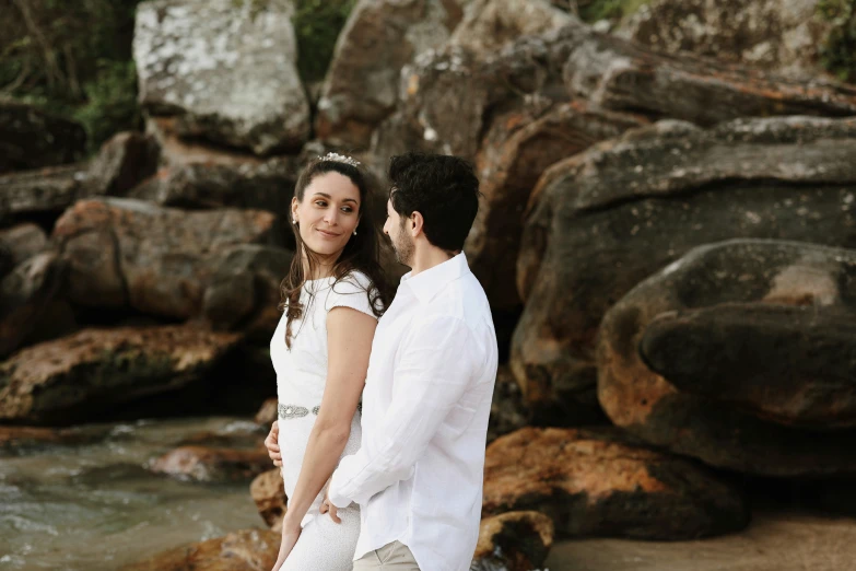 a couple standing on rocks near a river