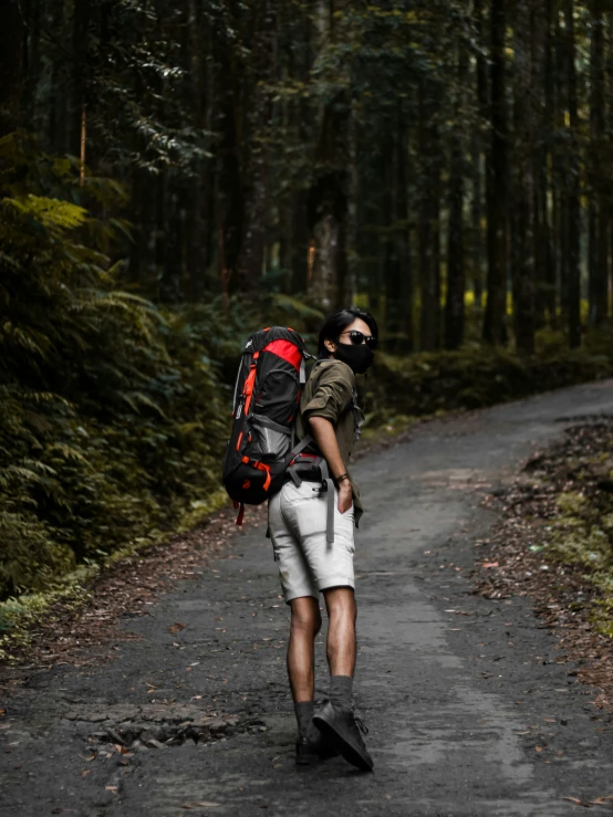 man in green jacket and white shorts hiking on a path