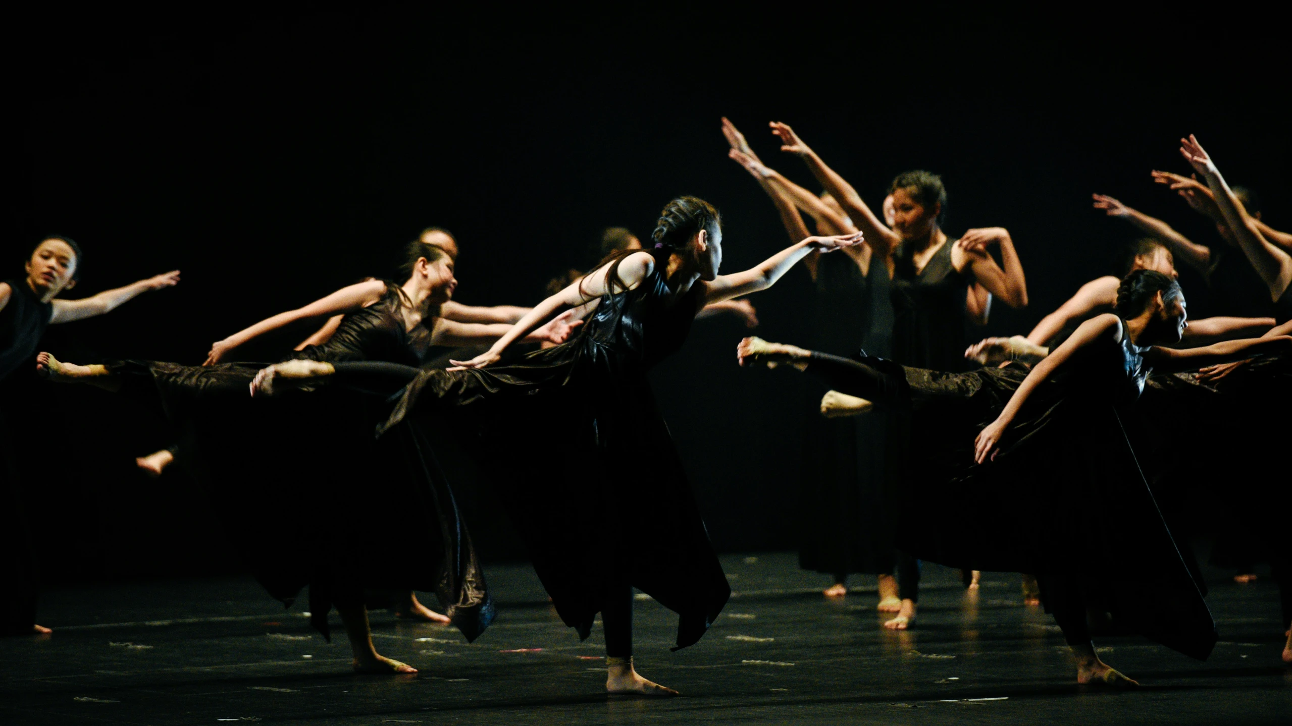 a dance group of women in long dresses with hands outstretched