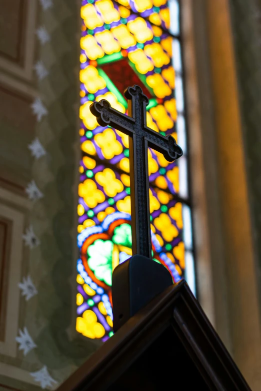 a cross sits inside of a stained glass window