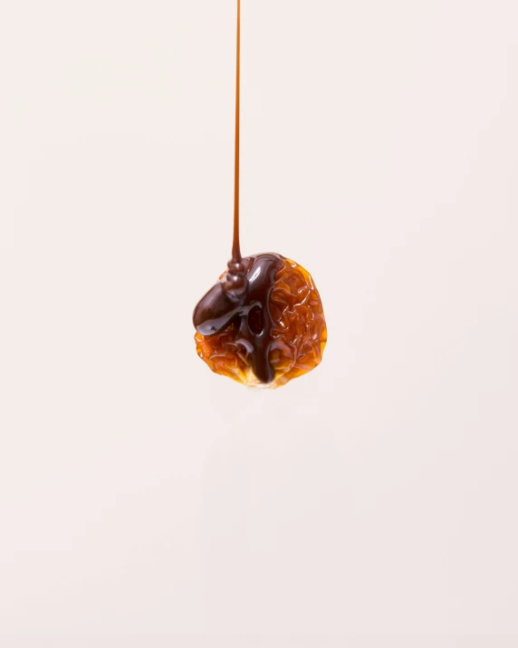 a piece of donut suspended from strings with liquid coming out of it