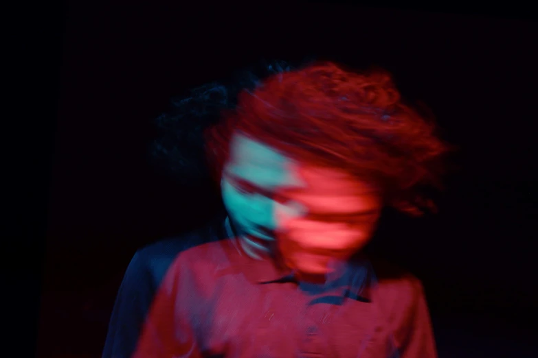 blurry image of person wearing red shirt standing in dark room