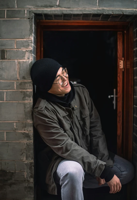 an elderly man with glasses sitting in a doorway