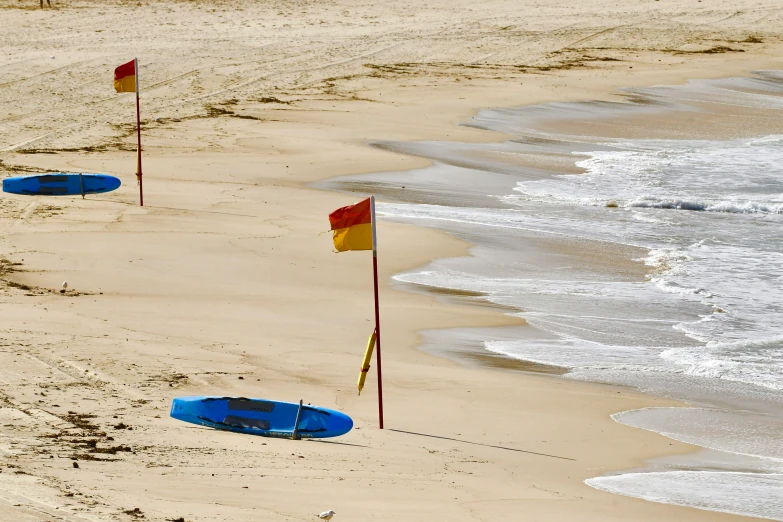 two flags near a small boat in the sand