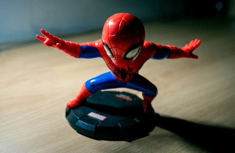 a toy spiderman stands next to a toy object