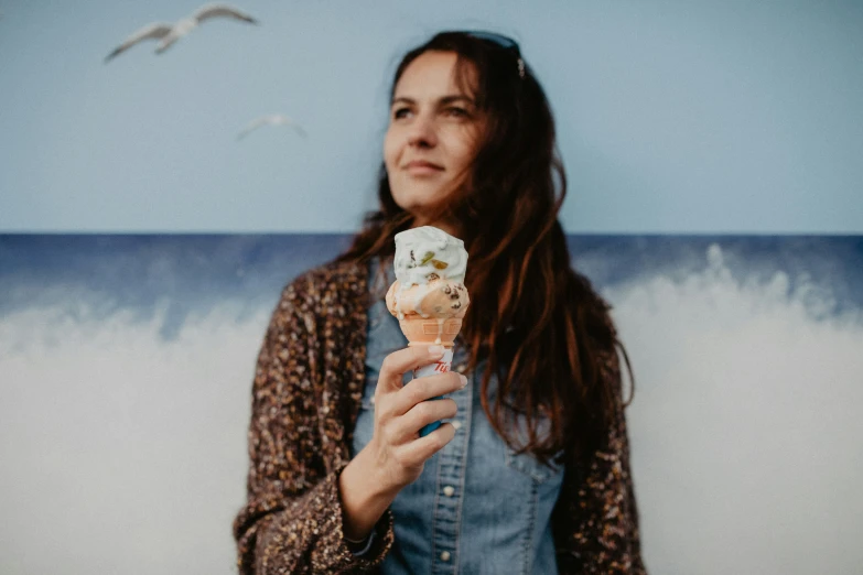 a woman holding a cupcake in front of a wave